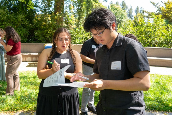Students stand outside with paper participating in a group activity