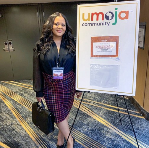 Antoinette Banks standing at a conference next to a sign that says Umoja