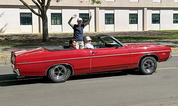 Sheri Atkinson waves from an open red convertible in the Picnic Day parade