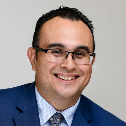 Tico Zendejas poses for a headshot in a blue suit, blue shirt, and paisley tie.