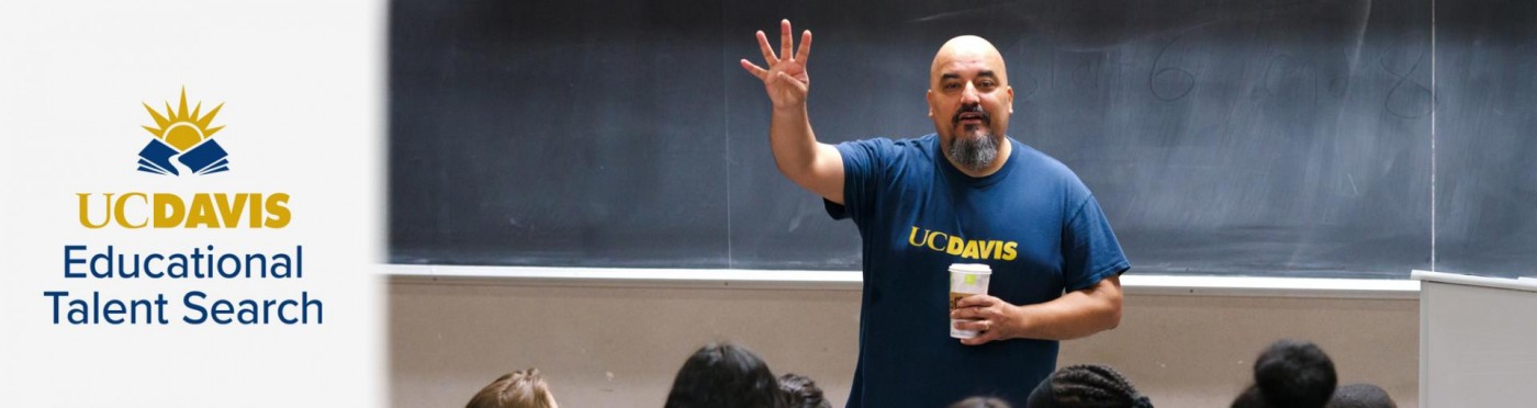 ETS Director Sam Blanco stands in front of students in front of chalkboard in college classroom