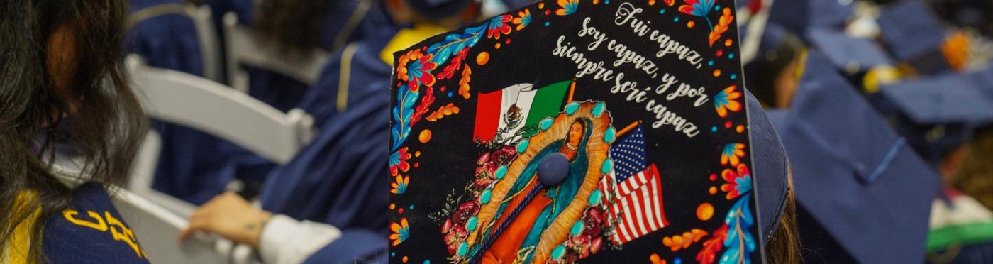 The back of a student's graduation cap during the ceremony that reads "Fui capaz, soy capaz, y por siempre seré capaz."