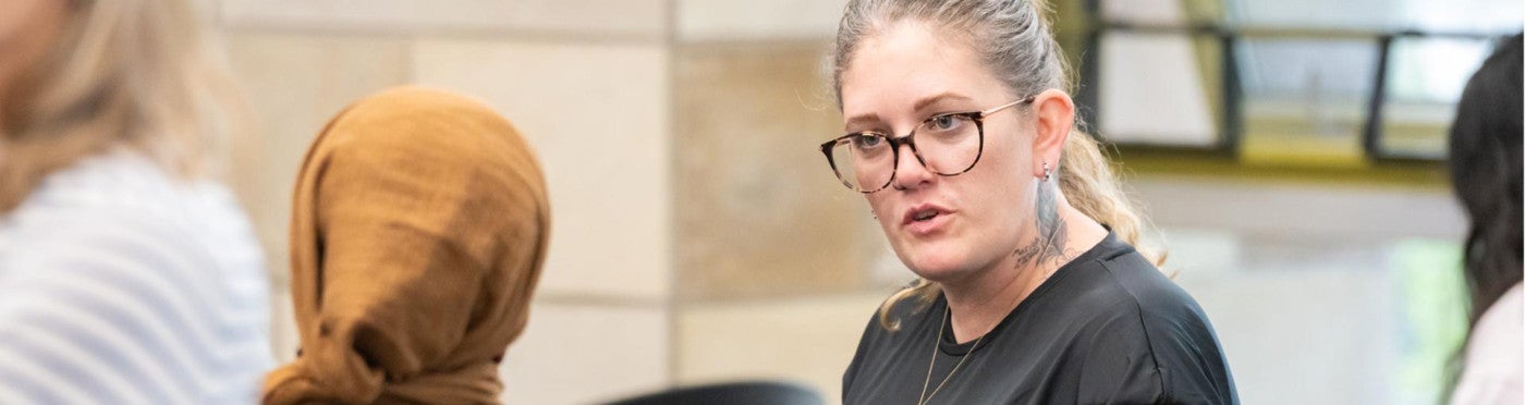 PhD student looking serious while in discussion with others at event