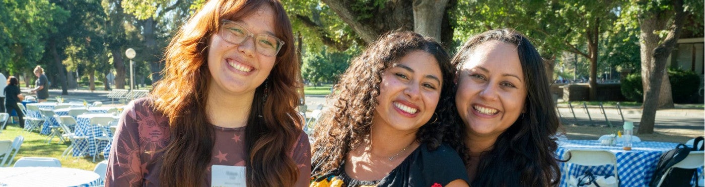 Three PhD students smiling outside at Fall Welcome event