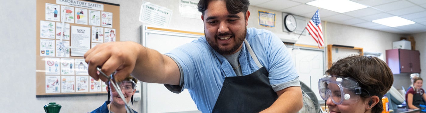 Graduate of minor program conducts science experiments with students as a student teacher