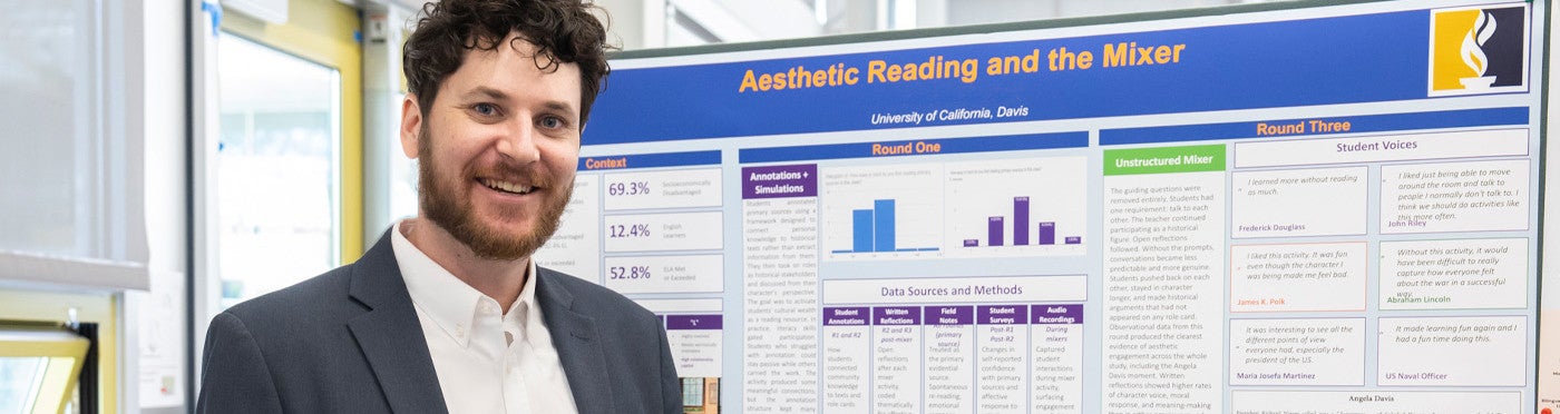 MA student standing in front of their poster