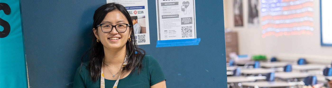 Credential student stands in doorway of her high school classroom