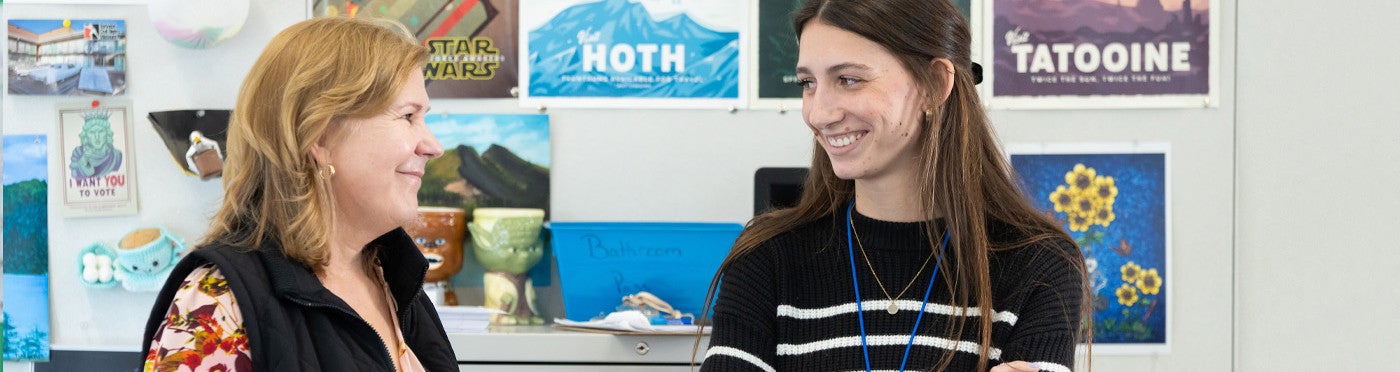 Teaching credential student and mentor teacher stand together smiling in elementary classroom