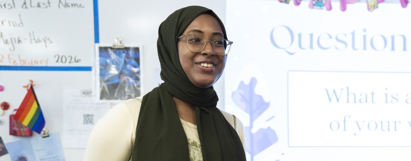 Student teacher standing in classroom  with whiteboard behind