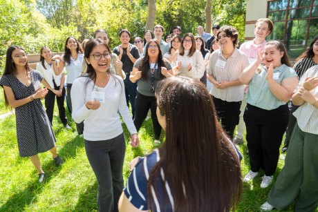 Two students play rock paper scissors while their classmates cheer them on
