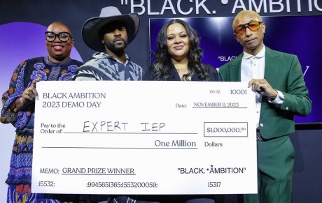 A photo of Antoinette Banks standing with three other people holding a large check for $1 million. 