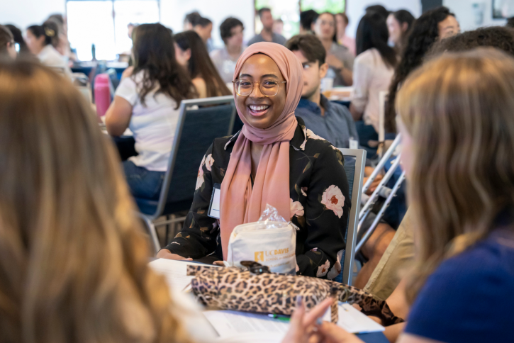 A student smiles at the others at her table.