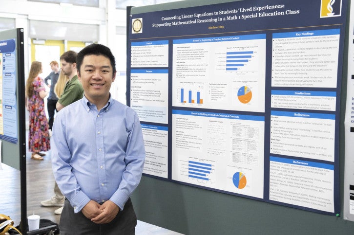 A man in a blue shirt smiles in front of an academic poster titled "Connecting Linear Equations to Students' Lived Experiences: Supporting Mathematical Reasoning in a Math 1 Special Education Class."