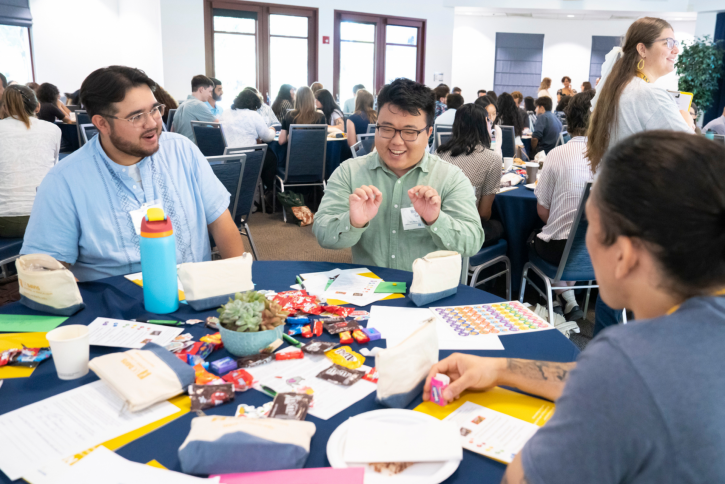 A student in a green shirt speaks to the others at his table.
