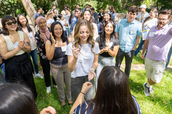 Two students play rock paper scissors while their classmates cheer.