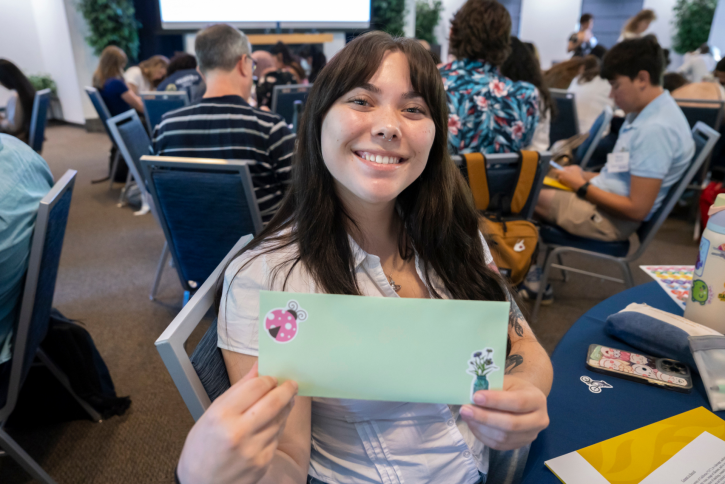 A student holds up a green envelope decorated with stickers.