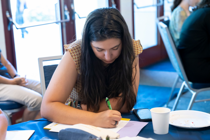 A student sits at a table, writing.
