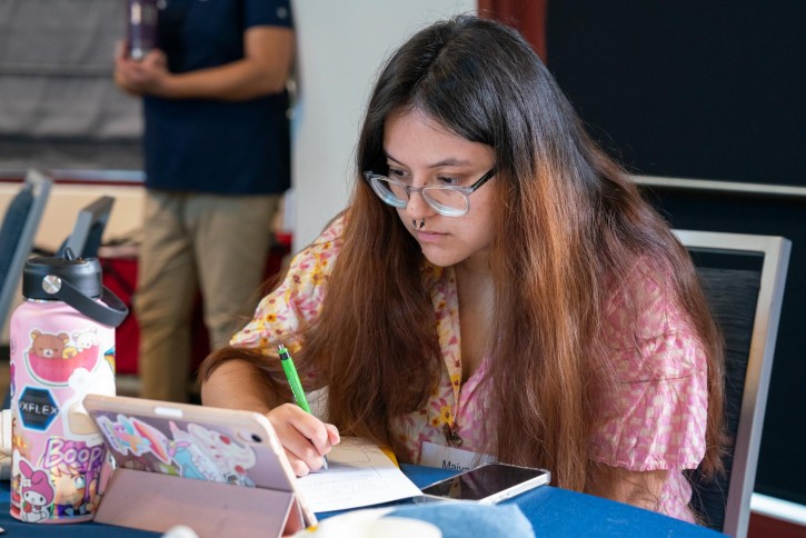 A student with long hair takes notes.