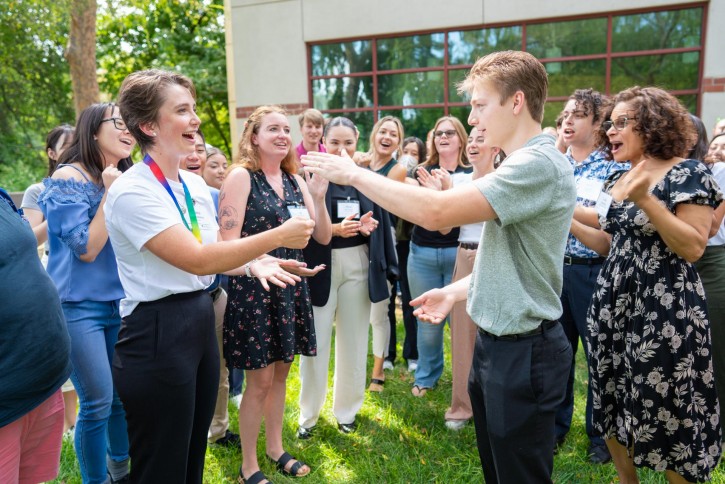 Students play rock paper scissors while the group cheers.