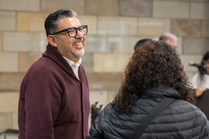 Danny C. Martinez addresses a woman wearing a down coat who is facing away from the camera.