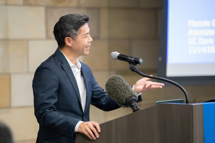 Kevin Gee stands at the podium and speaks into a microphone.