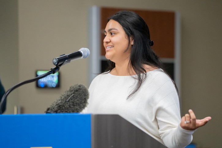 Isabella Cantu speaks into a microphone while standing at a podium.