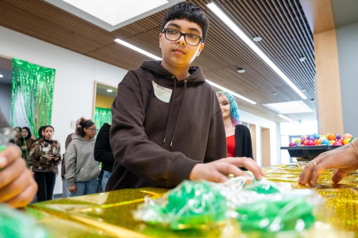 A boy looks down at a table covered with branded merchandise and a shiny yellow tablecloth.