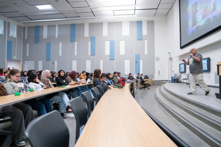 Samuel Blanco III stands at a podium, addressing an audience sitting in front of him.