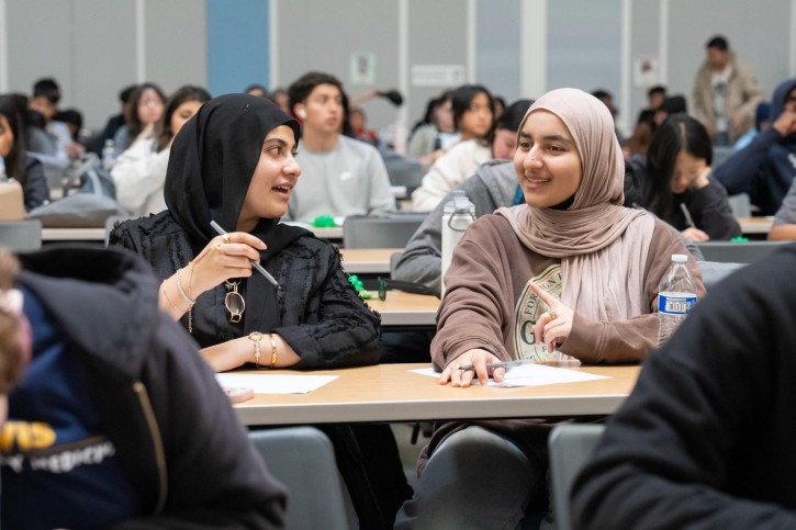 Two students wearing hijabs turn and speak to each other.