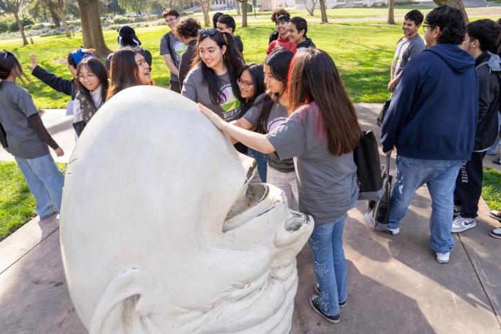 A girl places her hand on one of the UC Davis Egghead statues.