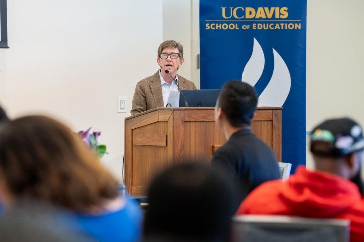 Dean Tom Smith stands at a podium and addresses the audience.