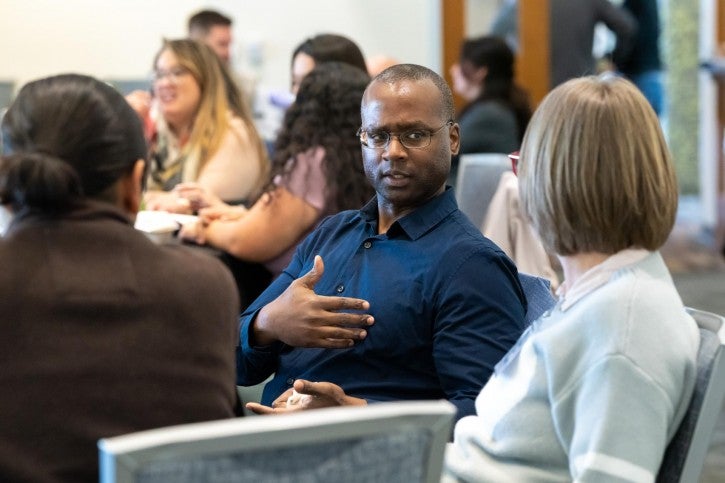 Prof. Darnel Degand speaks to a woman sitting next to him.