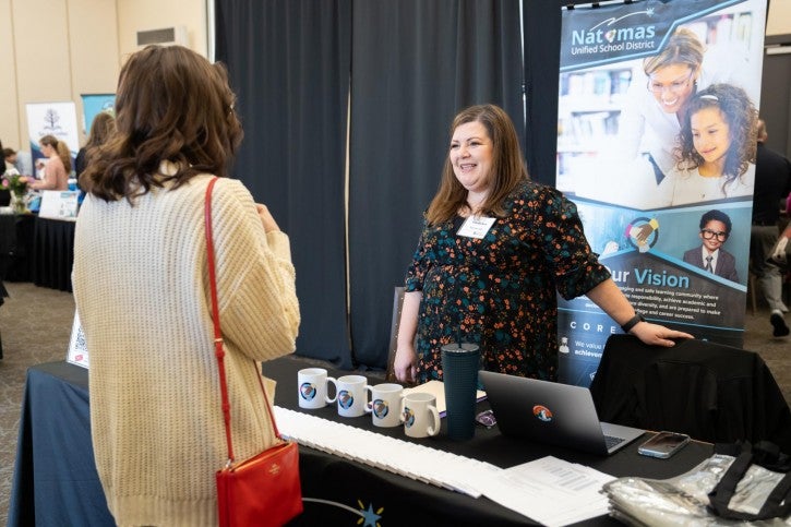 A school district rep speaks to a student, gesturing behind her.