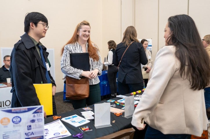 Two students speak to an employer.
