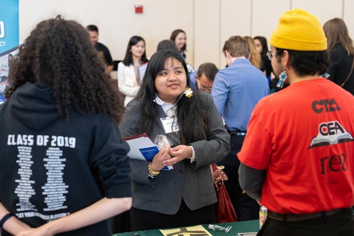 A student asks a question of two school representatives.