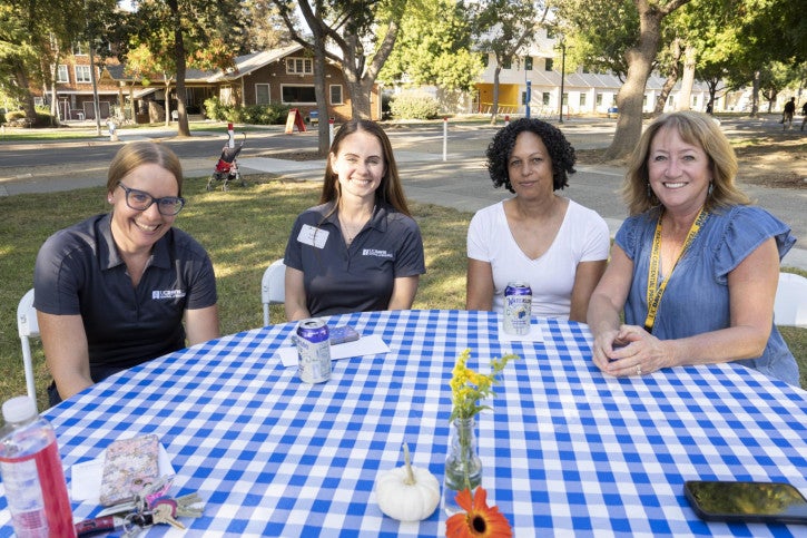 The School of Education Student Services team of four seats at a table and smiles.
