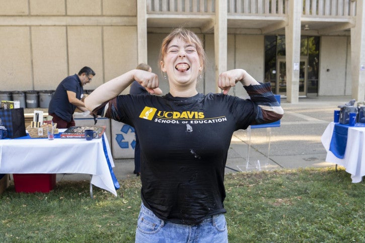 An alumna completes the frozen t-shirt competition first and poses with her arms flexed in the air.