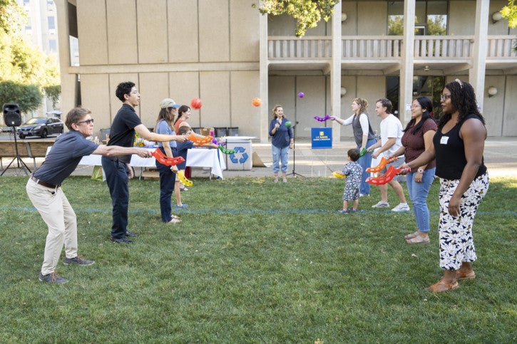 A group of students, faculty, and staff compete in a ball toss game.