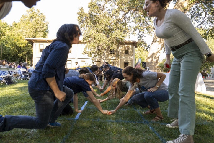 Two lines of 10 people face off in the game "Head, Shoulders, Knees, Ball."