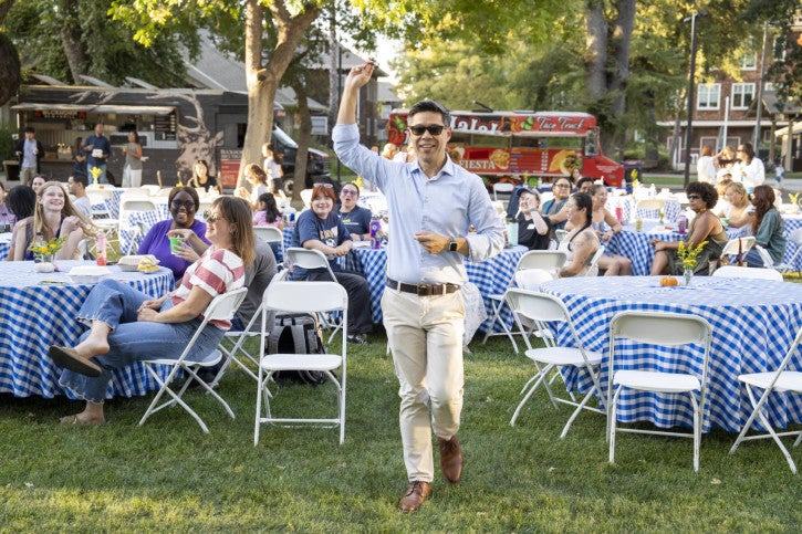 Kevin Gee, a raffle winner, stands and raises his arms in celebration.