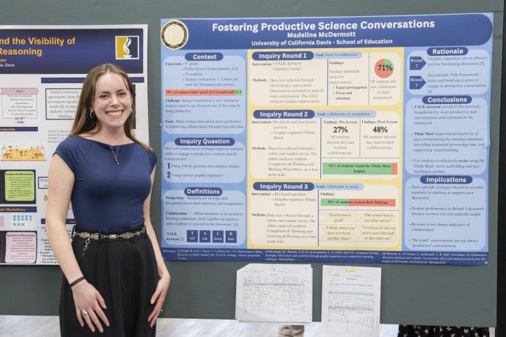 A woman in a blue shirt stands smiling next to a detailed academic poster titled "Fostering Productive Science Conversations".