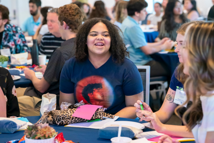 A student smiles, speaking to the others at her table.