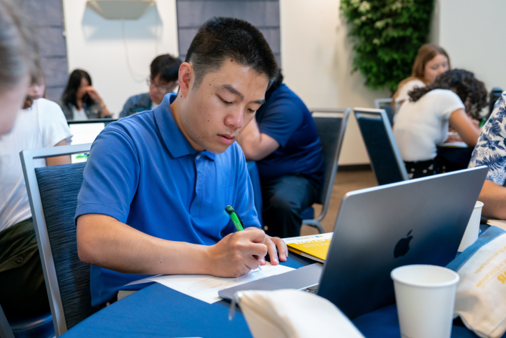 A student in a blue shirt takes notes