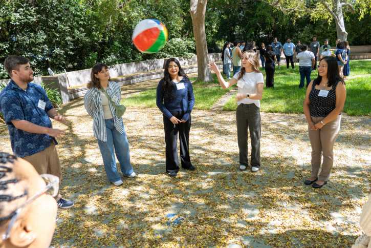 Students stand in a circle, tossing a beach ball.