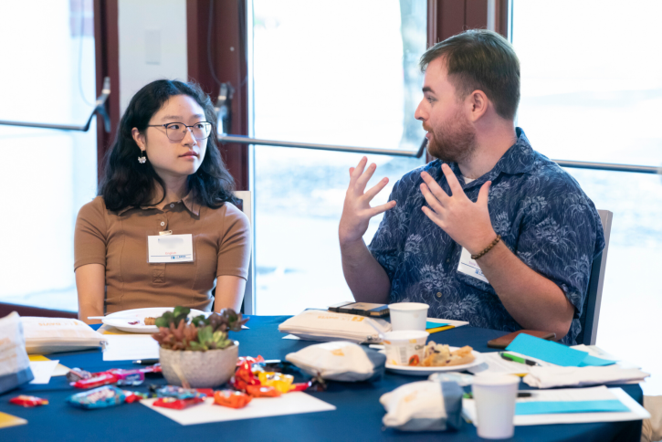 Two students sit at a table, talking.