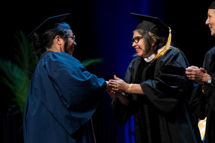 Credential grad Lydia shakes hands with her supervisor on stage.