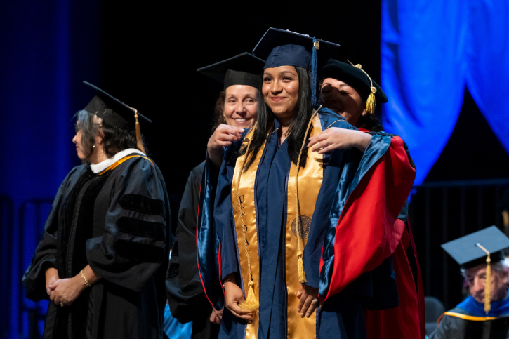 A credential grad smiles as she receives her cord.