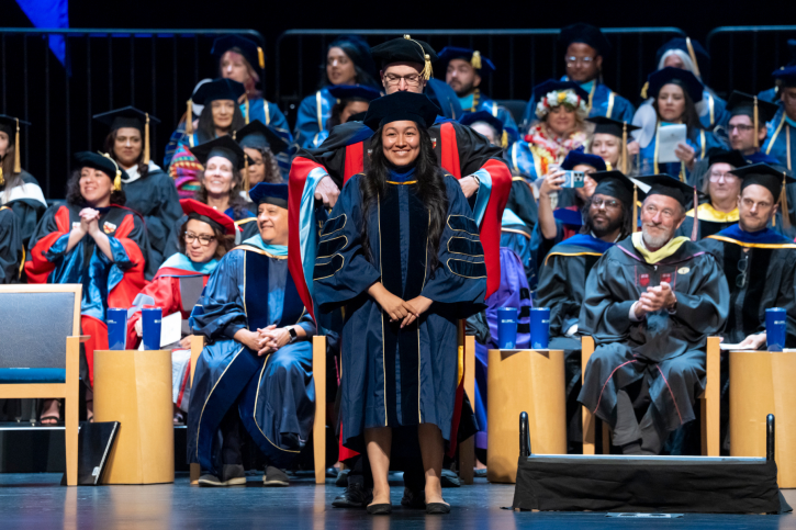 PhD grad Mariana smiles widely from the stage.