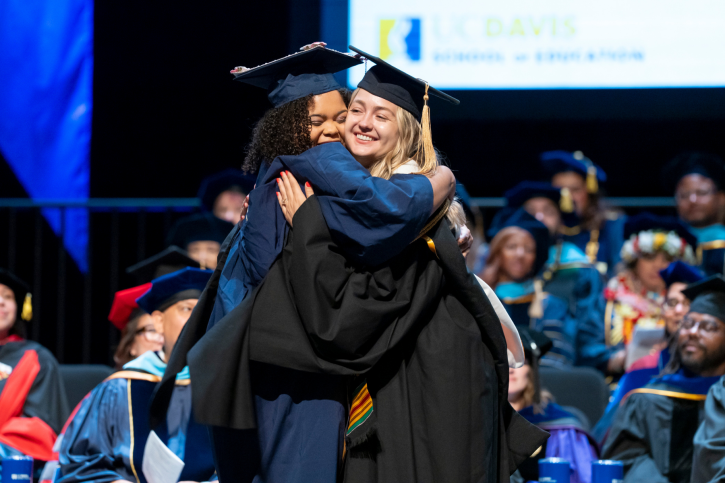 Credential student Kelsey hugs her supervisor as she crosses the stage.