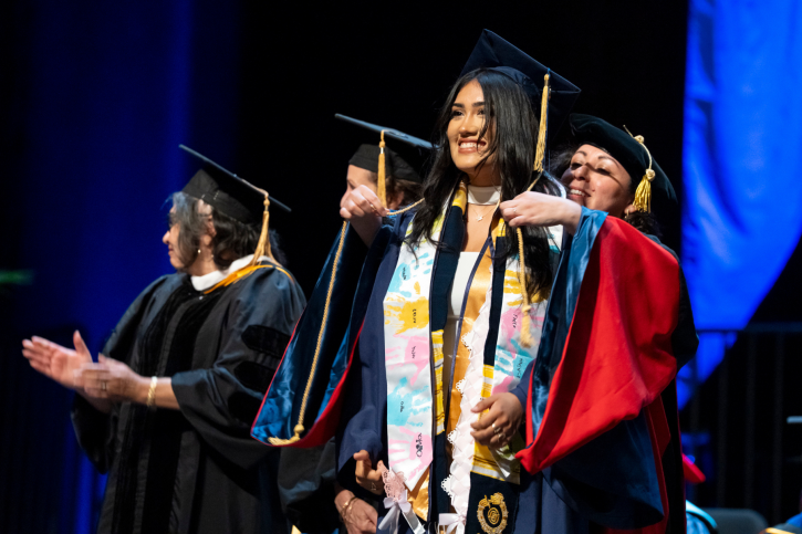 Credential grad Ruby smiles and looks at the audience as she receives her cord.